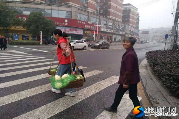 志愿者为卖菜的大妈挑起了“重担”